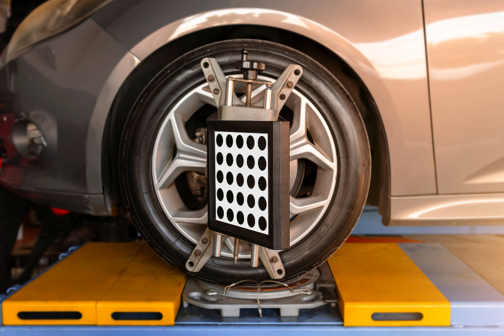 Alignment and ADAS Recalibration In Woodbine MD At Kit's Auto and Truck Repair. Image of wheel alignment sensor target clamp mounted onto the front tire of a car sitting on an alignment lift for ADAS recalibration and service.